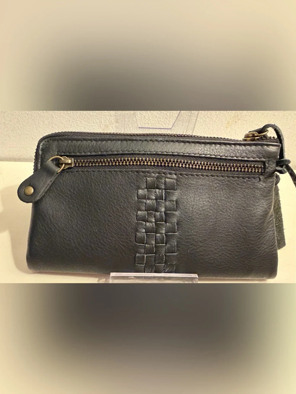Leather wallet in black with woven flap closure.